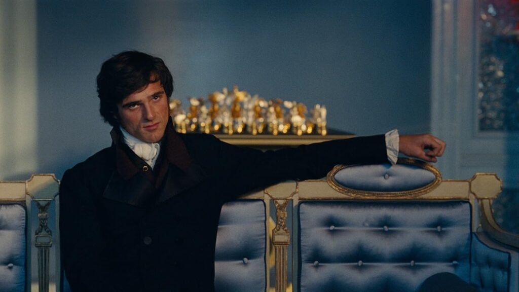 Jacob Elordi como Heathcliff sentado em uma sala elegante em O Morro dos Ventos Uivantes