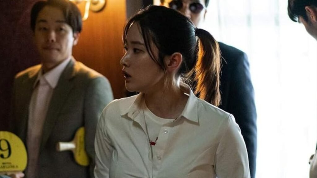 Park Ju-young, interpretada por Jeon Jong-seo, cercada por homens em cena de Barganha.