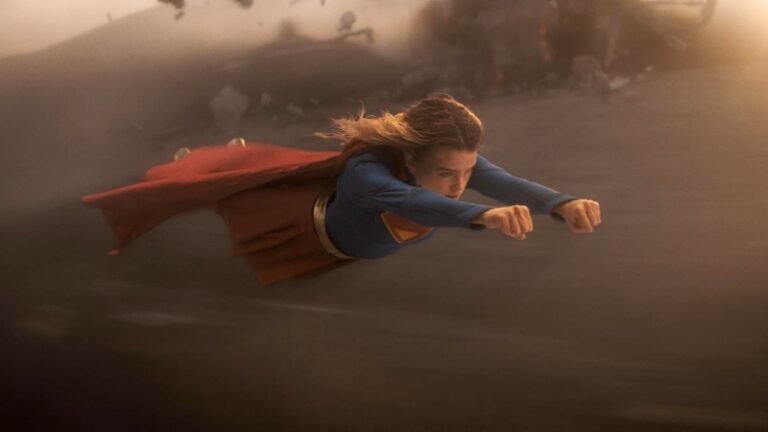 Heroína voando em meio à poeira em cena do filme Supergirl